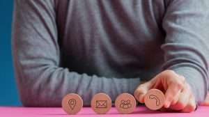 Man placing four wooden cut circles with contact and communication icons on them in a row